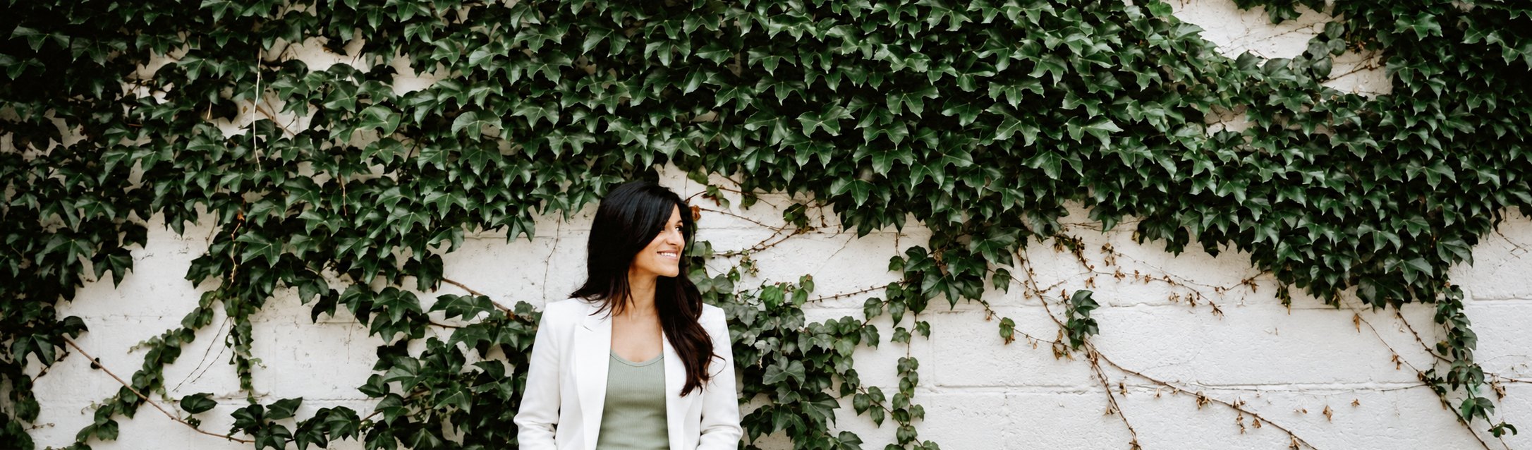 Dr K standing in front of an ivy-covered wall