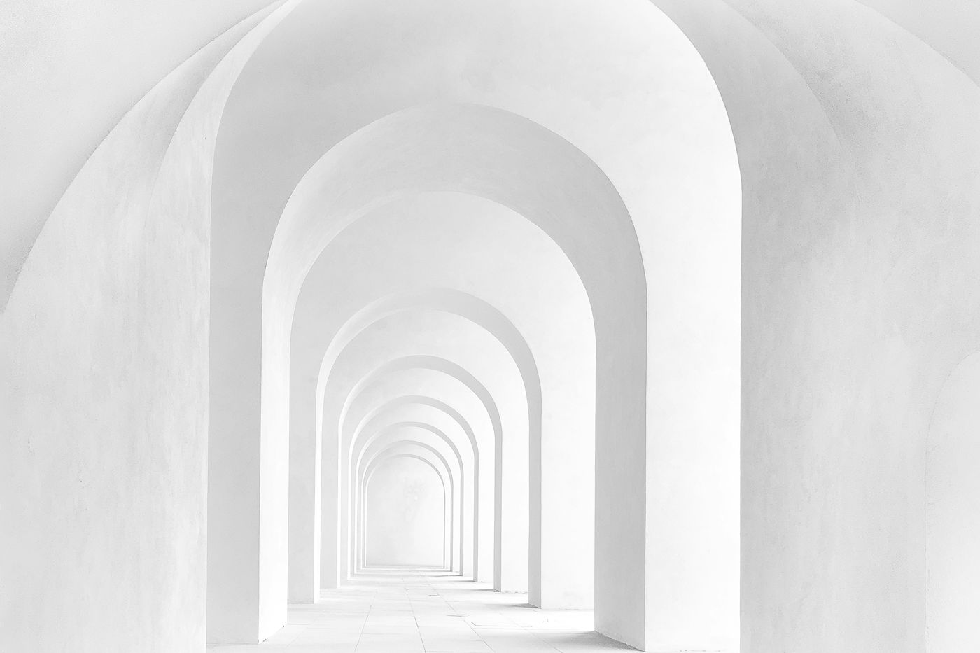 A white staircase leading through a long series of arches