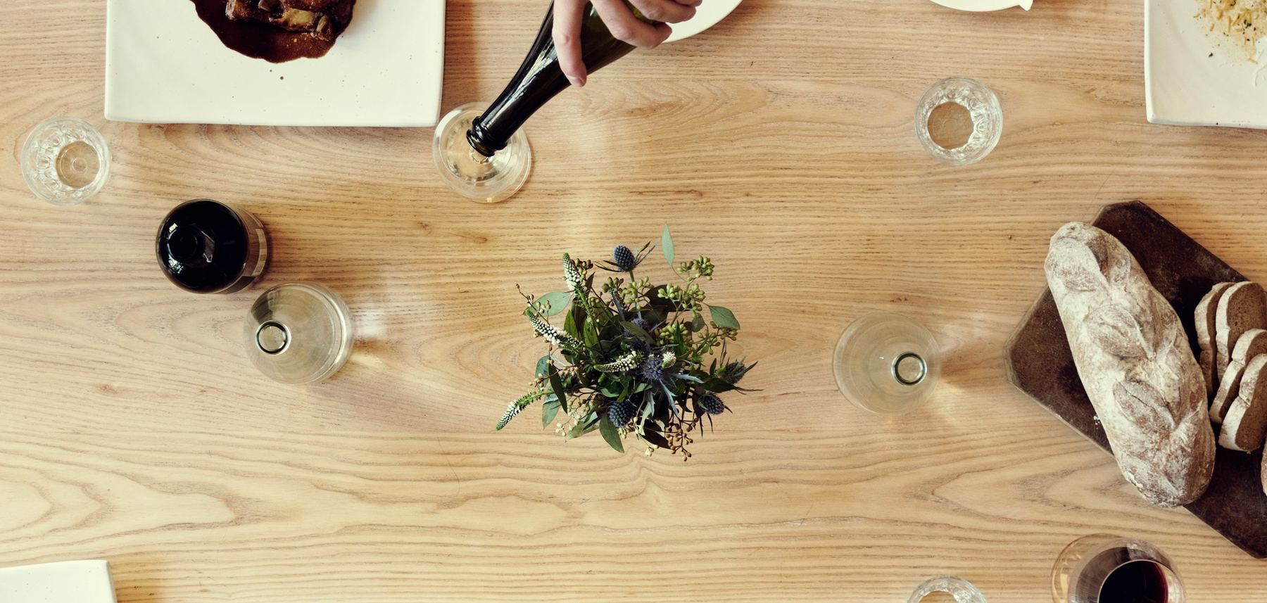 Overhead view of friends sharing plates of food around a wooden table