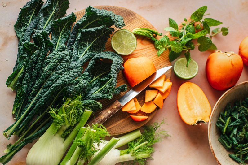Lacinato kale, fennel and persimmons on a cutting board